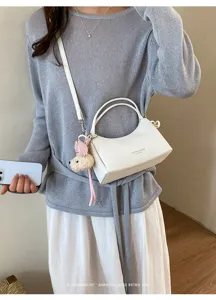 Minimalist white shoulder bag for women, trendy hobo handbag with cute bear pendant for commute.