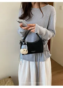 Minimalist black shoulder bag with cute plush charm, chic commuter handbag for women.