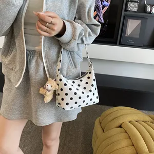 Fashionable polka dot shoulder bag for women, chic hobo handbag with cute bear pendant.