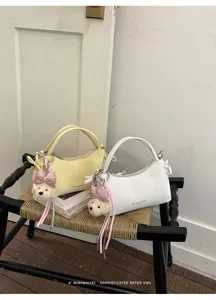 Minimalist small handbag, chic shoulder crossbody bag with cute bear pendant detail.