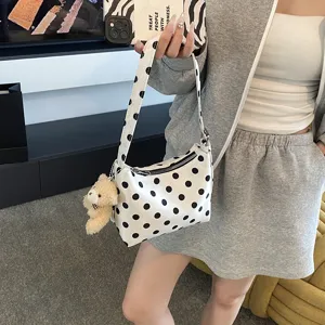 Detailed view of the chic black and white polka dot underarm bag with a cute bear pendant.
