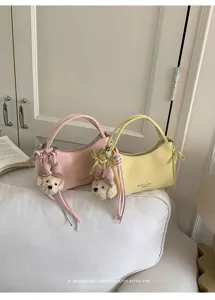 Minimalist women shoulder handbag, PU leather crossbody bag with cute bear pendant detail.