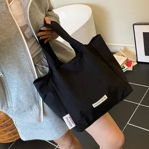 Detail view of black canvas tote bag with brand logo tag, casual daily design and sturdy handles.