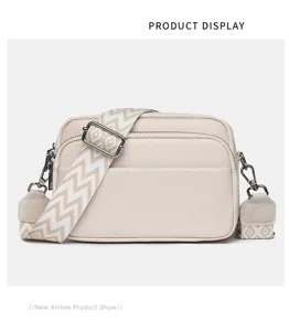Detail view of a multi-layer leather crossbody bag with chic geometric wide shoulder strap.
