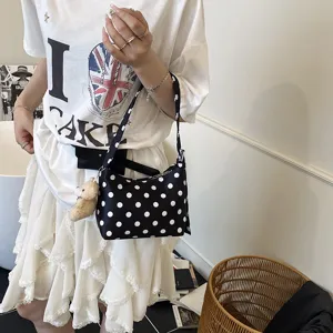 Detailed view of black and white polka dot underarm shoulder bag with cute bear pendant for women.