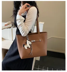 Brown leather tote bag detail with turn-lock closure and cute horse charm on shoulder.