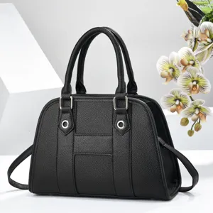 Vue détaillée du sac à main en cuir noir texturé avec anneaux et design central.