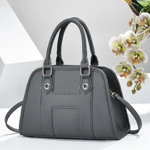 Détail de sac à main en cuir grainé gris avec texture fine, poignées et anneaux.