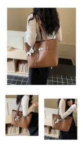 Stylish brown leather tote bag with large capacity and charming pendant for women daily commute.