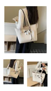Detail view of stylish beige tote bag with chic horse charm and premium shoulder straps.
