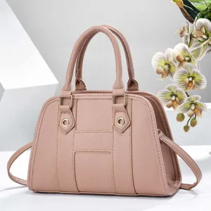 Vue détaillée du sac à main rose en cuir grainé avec double poignée et accessoires métalliques.
