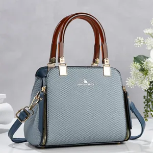 Vue détaillée du sac à bandoulière en tissu bleu avec poignée en résine et quincaillerie dorée.