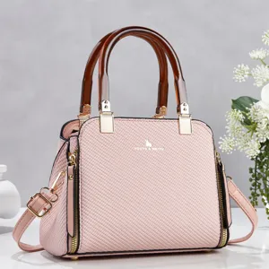 Vue détaillée du sac à main texturé rose avec poignées marron et accessoires dorés.