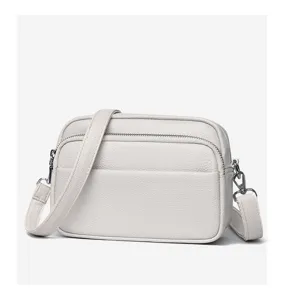 Detail view of the white leather crossbody bag, showing soft texture and fine metal zipper.