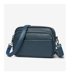 Dark blue leather crossbody bag detail, premium soft cowhide small square bag texture.