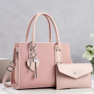 Pink women's commuter handbag set with matching pouch and heart key charm stylish design.