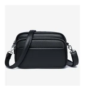 Detailed view of a black genuine leather crossbody bag with multiple zippers and strap.