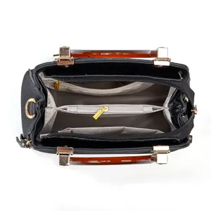 Sac à main noir avec poignées en résine ambrée, intérieur spacieux à compartiments.