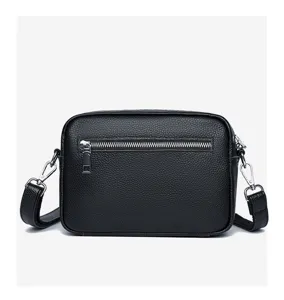 Detailed view of black genuine leather crossbody bag with front zipper and hardware.