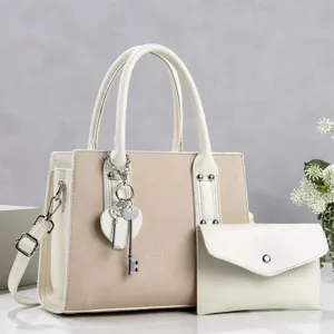 Detail view of a chic beige and white tote bag with shoulder strap, charm, and pouch.