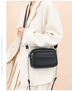 Detail shot of the black leather crossbody bag featuring metal chain and soft cowhide texture.