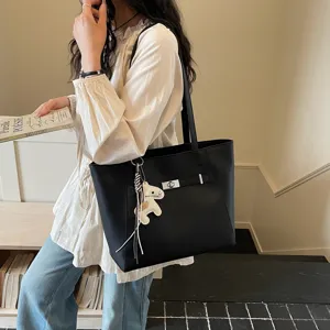 Detail shot of a black tote bag featuring a stylish belt lock and cute horse charm, perfect lifestyle.