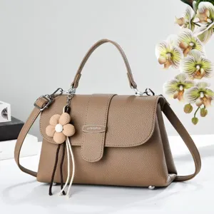 Vue détaillée de sac à main texturé en similicuir marron avec joli pendentif de fleur.