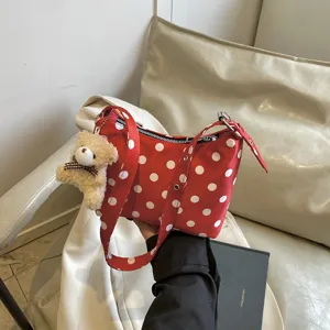 Red polka dot cloth shoulder bag detail view with cute plush bear pendant accessory for women.