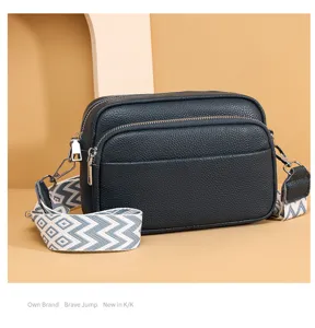Stylish multi-layer leather crossbody bag with wide patterned strap for women commute.