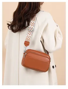 Detailed view of women brown leather crossbody bag with chic geometric wide shoulder strap.
