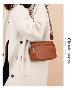 Close-up detail of the brown leather multi-layer crossbody bag with patterned wide strap.
