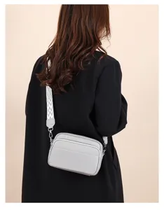Detail shot of women crossbody bag with wide patterned strap and multi-layer design.