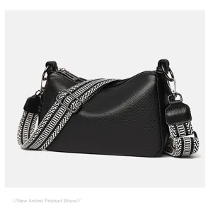 Black leather shoulder bag with wide geometric strap, chic crossbody pillow bag for women.
