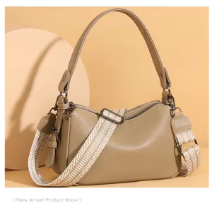 Close-up detail of khaki leather shoulder bag texture, metal hardware, and wide strap.