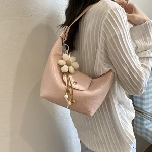 Dettaglio in primo piano della borsa a tracolla rosa elegante con ciondolo floreale.