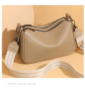 Khaki leather shoulder crossbody pillow bag featuring double zippers and wide woven strap.