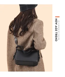 Detailed view of genuine leather black saddle bag worn on shoulder with wide strap.