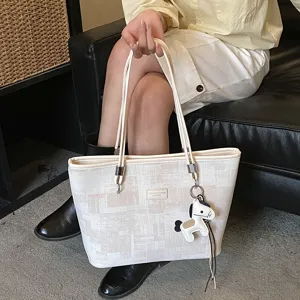 Dettaglio della borsa tote casual con motivo geometrico e ciondolo a forma di cavallo.