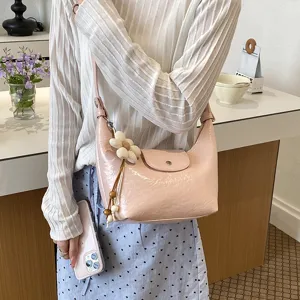 Borsa a tracolla hobo dumpling in pelle verniciata rosa con ciondolo floreale per lo stile.