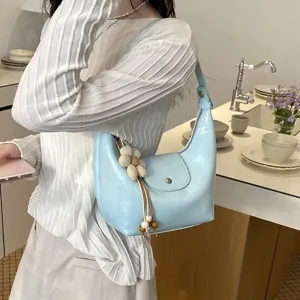 Vista dettagliata della borsa a spalla blu chiaro, con ciondolo floreale chic e stile casual.