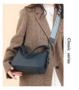 Close-up detail shot of dark green leather shoulder bag with wide blue patterned strap.