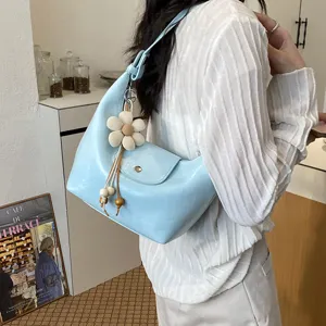 Dettaglio della borsa a tracolla hobo azzurra casual con grazioso ciondolo a forma di fiore.