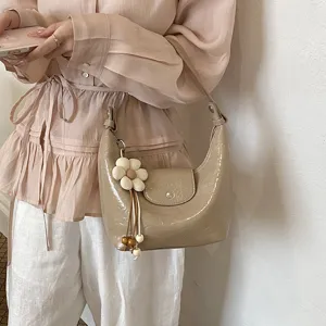 Vista dettagliata della borsa a tracolla dumpling lucida casual con grazioso ciondolo floreale.
