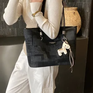 Vista di dettaglio della grande borsa shopper scura fantasia con ciondolo cavallo bianco.
