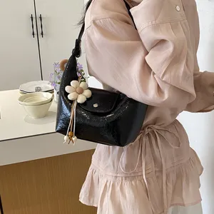 Vista dettagliata dell'elegante borsa a tracolla nera stropicciata con grazioso ciondolo a fiore.