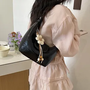 Borsa a tracolla a mezzaluna in vernice nera con grazioso ciondolo floreale elegante.