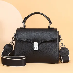 Detailed view of the black leather shoulder bag showcasing texture, metal lock, and wide strap.