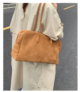Detalle de un gran bolso de hombro de ante marrón y una muy elegante bolsa de mano.