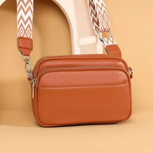 Brown leather multi-pocket crossbody bag with wide geometric strap for women daily commute.