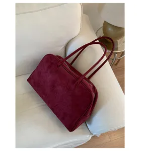 Vista detallada del elegante bolso de hombro de ante burdeos con textura premium.